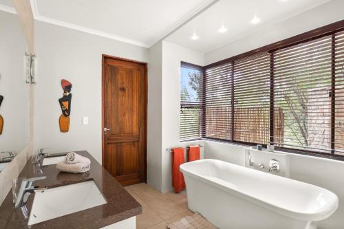 baño con una gran bañera blanca y una ventana en Elements Private Golf Reserve House 197, en Bela-Bela