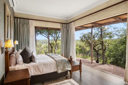 ein Schlafzimmer mit einem Bett und einem großen Fenster in der Unterkunft Elements Private Golf Reserve House 197 in Bela-Bela