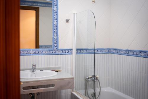 y baño con ducha, lavabo y bañera. en Hostal Cabo Roche, en Conil de la Frontera