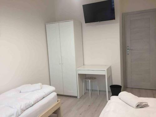 a room with two beds and a desk and a tv at Apartament Kraków Arena in Krakow