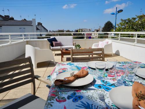 une table avec des assiettes et des verres sur un balcon dans l'établissement KER HERA.Bain de lumière à ETEL, à Étel