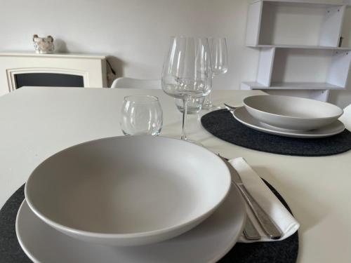 a white table with two plates and wine glasses at UCUPPU apartments in Carloforte