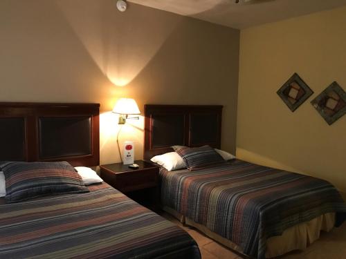 Cuatrociénegas de CarranzaにあるHOTEL QUINTA SANTA CECILIAのホテルルーム ベッド2台&ランプ付