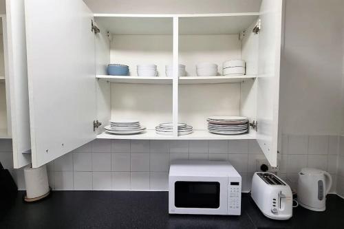 a kitchen with a microwave and plates on shelves at 2 Bedroom apartment in Kennington London in London
