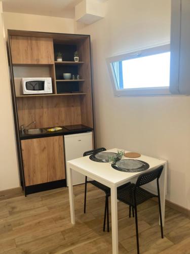 a small kitchen with a white table and two chairs at Le mini cosy in Gaillon