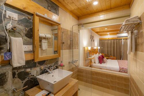 a bathroom with a sink and a bedroom at StayVista at Sarog Cottage at Daafi in Shimla