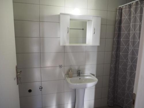 a white bathroom with a sink and a mirror at Apartments dimitra in Kanallákion