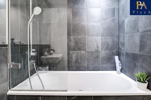 a bathroom with a bath tub and a sink at Pluxa Azure Cubic - Azure Cityview, Corporate Stays Welcome in Birmingham