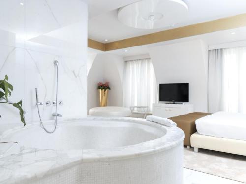 a white bathroom with a tub and a bedroom at Boscolo Nice Hotel & Spa in Nice