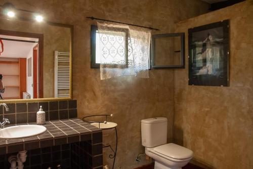 uma casa de banho com um WC, um lavatório e um espelho. em Cal Cabrer em Masarach