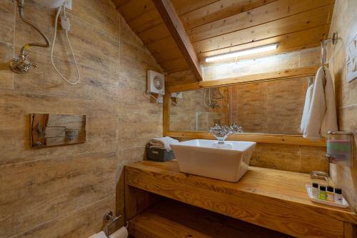 a bathroom with a sink on a wooden counter at StayVista at Sarion Cottage at Daafi in Theog