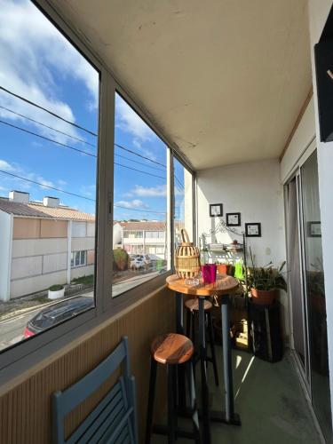 un balcon avec une table, des chaises et une fenêtre dans l'établissement appartement 4/6 pers à 300 m de la plage, à Saint-Hilaire-de-Riez