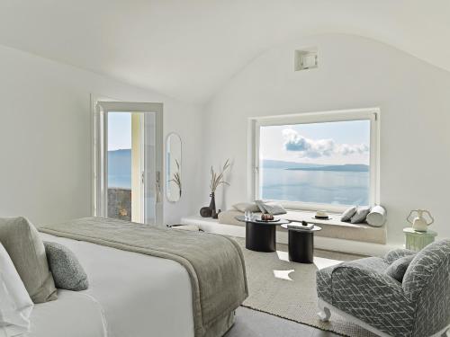 a bedroom with a bed and a couch and a window at Canaves Oia Suites - Small Luxury Hotels of the World in Oia