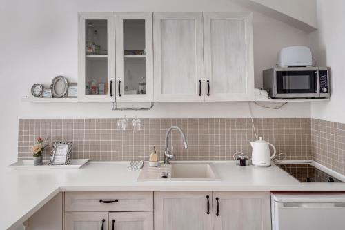 a kitchen with white cabinets and a sink and a microwave at Apartments With The Lions in Prague