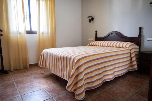 a bedroom with a bed with a striped blanket on it at Apartamentos Majadales de Roche in Conil de la Frontera
