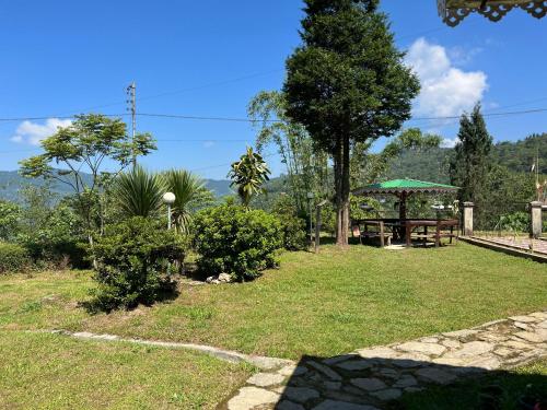 um jardim com uma mesa e um guarda-sol verde em Dilpali Home Cum Farm stay em Sukhia Pokhari