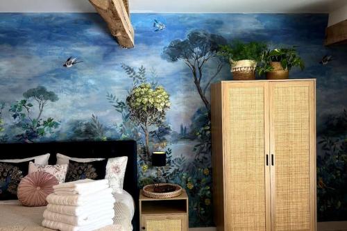 a bedroom with a painting on the wall at La Colline de Tilleul - De La Colline - Beautiful Cottage Near Aubeterre in Saint-Romain