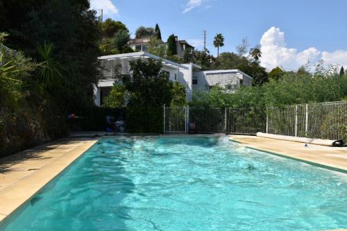 une piscine avec de l'eau bleue devant une maison dans l'établissement Villa Malibu by Connexion, à Mandelieu-la-Napoule