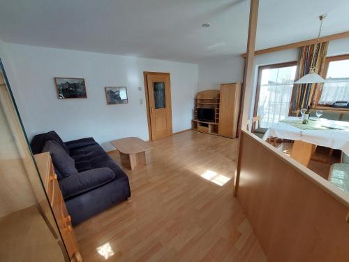 - un salon avec un canapé bleu et une table dans l'établissement Appartements Bodenland, à Wildschönau
