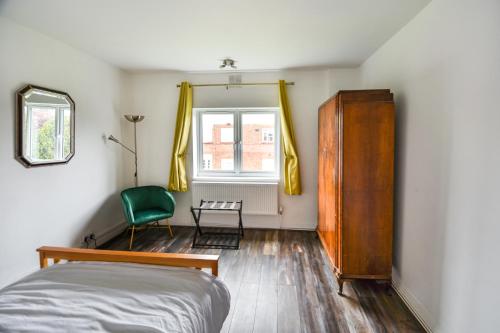 a bedroom with a bed and a chair and a window at 2BR Hendon Flat - Free Parking & Bus stop outside in Hendon