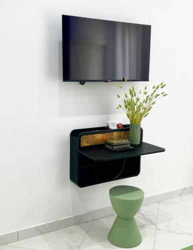 a tv hanging on a wall with a green chair at RaRoom Supernova H in Torre del Greco