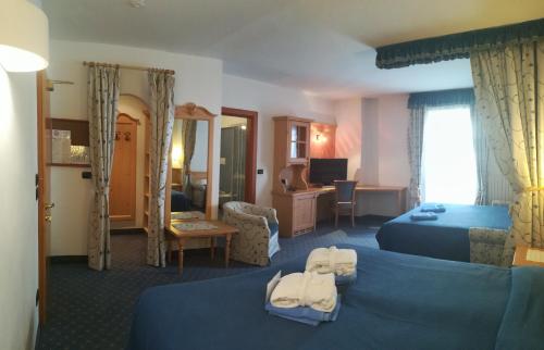 a hotel room with two beds with towels on them at Hotel Isolabella Wellness in Fiera di Primiero