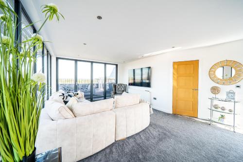 a white couch in a living room with windows at Luxurious 2-Bedroom Penthouse Apartment with Stunning Glass-Wall Views in Barnsley Town Centre in Barnsley