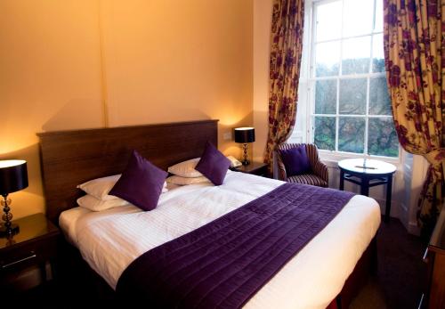 een slaapkamer met een bed met paarse lakens en een raam bij Royal Scots Club in Edinburgh
