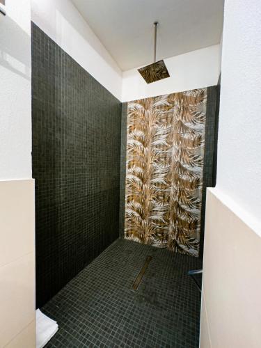 a bathroom with a shower with black tiled walls at Hotel Lido Beach PHG in Oristano