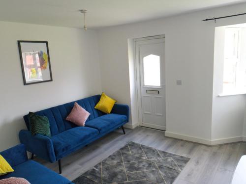 a living room with a blue couch and yellow pillows at Latchford Mews in Warrington