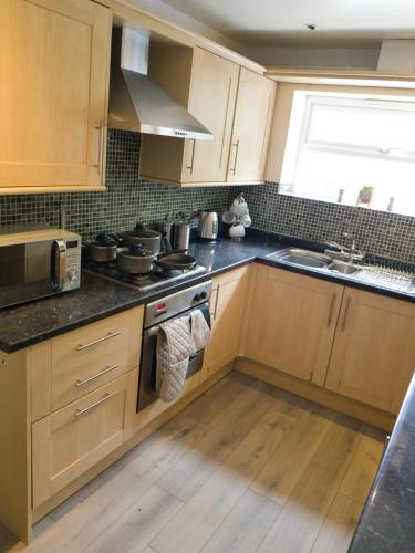 a kitchen with wooden cabinets and a stove top oven at Latchford Mews in Warrington