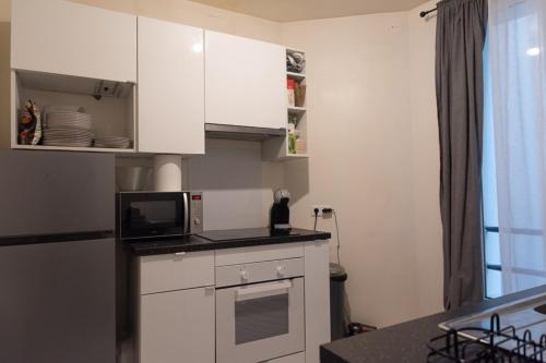 une petite cuisine avec des armoires blanches et un micro-ondes dans l'établissement Charming studio near Parc Clichy, à Paris