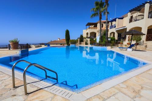 a large swimming pool with blue water in front of a building at Daniel's Apt - Magical Views in Tsadha
