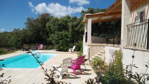 - une piscine avec 2 chaises roses à côté d'une maison dans l'établissement Villa Piscine-SPA vue grandiose., à Faugères