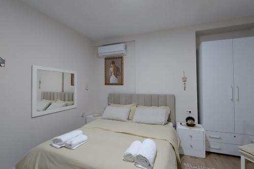 a white bedroom with a bed with towels on it at Tranquil Oasis for Two in Tirana