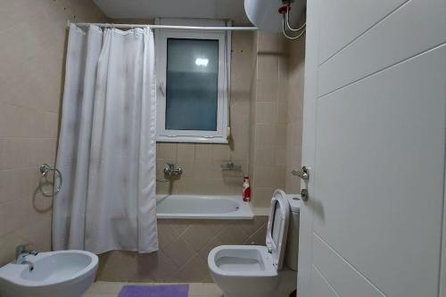 a bathroom with a toilet and a tub and a sink at Tranquil Oasis for Two in Tirana