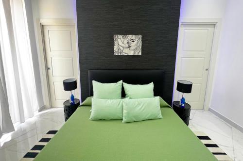 a bedroom with a green bed with two pillows at RaRoom Supernova in Torre del Greco