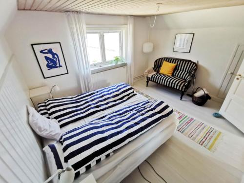 1 dormitorio con 1 cama de rayas y 1 silla en Seaview en Hylleholt