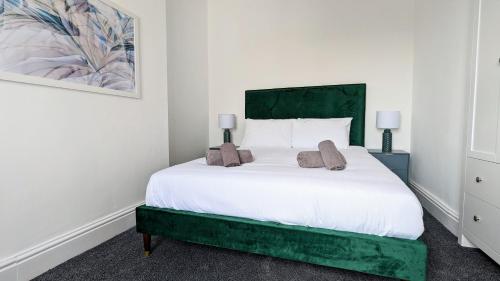 1 dormitorio con cama blanca y cabecero verde en West Shore Apartment by Seaside Llandudno en Llandudno