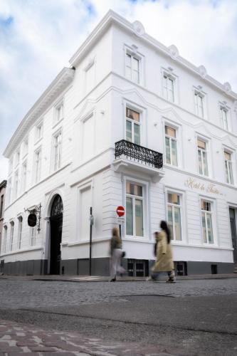 two people walking in front of a white building at Hotel du Théâtre in Bruges