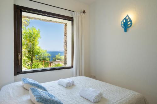 a bedroom with a window and a bed with towels at [VILLETTA VISTA MARE] Cala dei Ginepri con Giardino in Cala Bitta