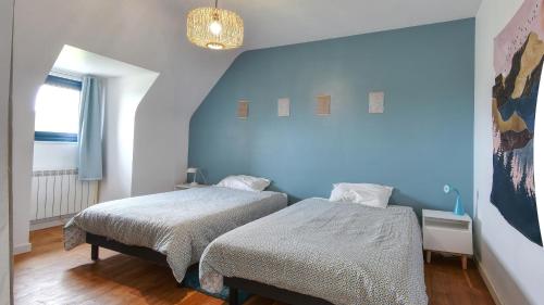 une chambre avec deux lits et un mur bleu dans l'établissement Grande villa 6 personnes à 200m de la mer . Récemment rénovée., à Moëlan-sur-Mer