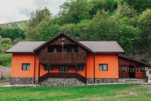 una casa naranja con techo negro en Cabana Bombonel, en Gura Teghii