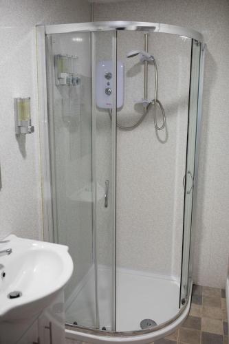 a shower with a glass door next to a sink at Ballycastle 7A Diamond 2 bedroom apartment in Ballycastle