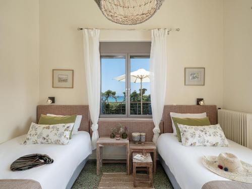two beds in a room with a window at The House By The Sea in Kato Daratso