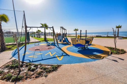 un parque infantil con columpios en la playa en sea view villa with garden, en Agadir
