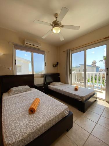 a bedroom with two beds and a ceiling fan at Sea View Villa in Agia Thekla in Ayia Napa