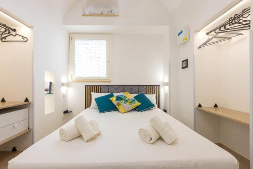 a white bedroom with a large white bed with blue pillows at Coral - 30 passi dalla Spiaggia della Purità in Gallipoli