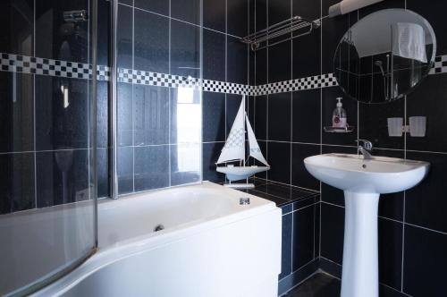 a bathroom with a sink and a bath tub and a mirror at Manor View - 1 Bedroom Apartment - Pendine in Pendine