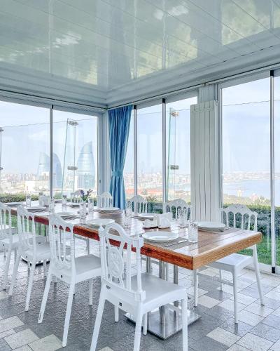 a dining room with a long table and white chairs at Badam d'Art Boutique Hotel in Baku